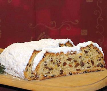 Angeschnittener Stollen mit Rosinen, bedeckt von Butter-Zucker-Schicht und Puderzucker